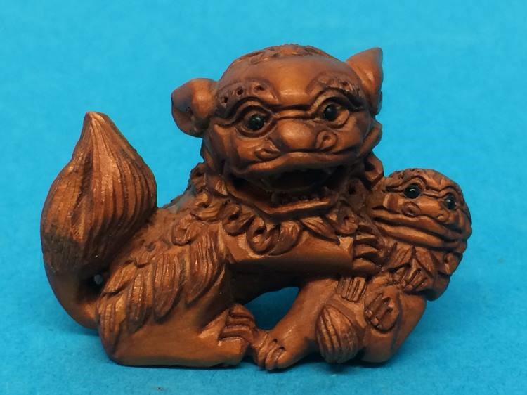 A carved wooden Netsuke in the form of a dog of Fo