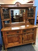 An oak Art and Crafts bow front sideboard, the raised mirrored back flanked by bow front lead