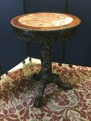 An Oriental carved centre table, the circular top with inset coloured marble below a carved frieze