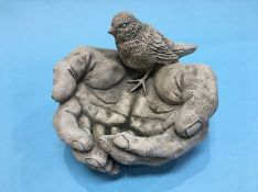A small bird bath in the form of a pair of hands