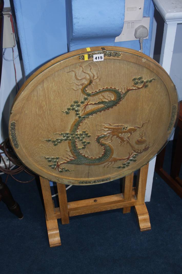 An oak circular folding table, decorated with a dragon