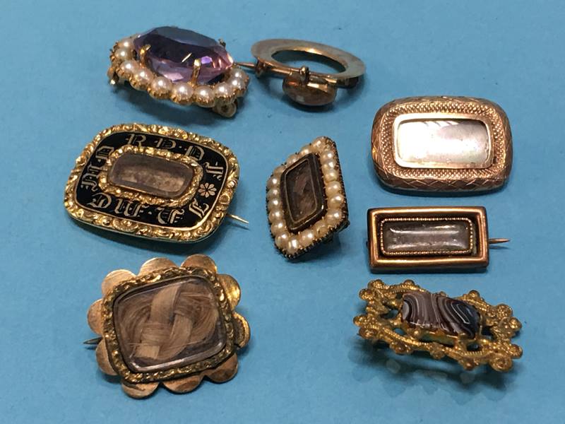 A collection of various yellow metal brooches