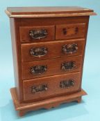 A miniature oak chest of two short and three long graduated drawers