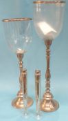 A pair of hurricane lamps and a pair of tall slender candlesticks