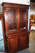 A Victorian style bookcase with double doors, below two cushion drawers and two cupboard doors