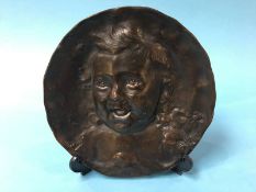 A bronze circular wall plaque depicting a babies face, stamped E. Devy, 22cm diameter