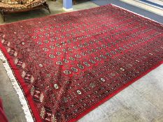 A Pakistani Bokhara carpet, the madder red ground bearing seven rows of 22 guls, multiple guard