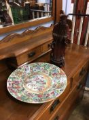 A Chinese canton enamel wall plate and a carved hardwood figure, 34cm diameter