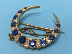 A crescent shaped yellow metal brooch, mounted with diamonds and sapphires, 5.8g 3.2cm diameter 0.25