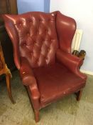 A burgundy Chesterfield wing back armchair