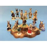 13 Royal Doulton Bunnykins figures, together with a stand