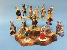 13 Royal Doulton Bunnykins figures, together with a stand