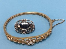 A yellow metal bracelet, mounted with seed pearls and a brooch The bangle is not hallmarked Total