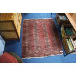 A Pakistani Bokhara rug, the madder red ground bearing two rows of guls, main sunburst border and