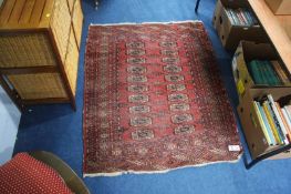 A Pakistani Bokhara rug, the madder red ground bearing two rows of guls, main sunburst border and