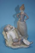 Lladro group of a boy lying on a bed of straw with a young girl looking down