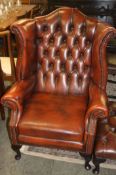 A Chesterfield high back armchair and footstool