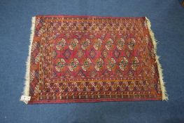 A Pakistani Bokhara rug, the madder red ground wit