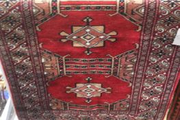 An Afghan rug with three large medallions bearing flowers and stars and multiple guard stripes. 91cm