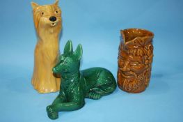 A Continental green coloured pottery dog, an Absinthe jug and a mask jug (3)