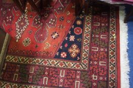 A machine made rug, the red ground with geometric medallions and a serrated leaf border. 200cm x