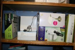 A shelf of miscellaneous; boxed pressure cooker, standing fan etc.