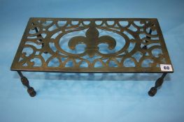 A 19th century pierced brass trivet, 46cm wide