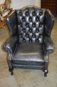 A blue leather wing back armchair