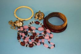 An amber coloured bangle, two other bangles, two necklaces, a lion brooch and a bracelet.
