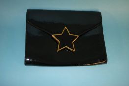 Black patent clutch bag with large star fastening, with dust bag