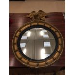 A circular gilt mirror with eagle finial