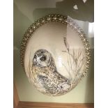 A framed and glazed ostrich egg with pearl surround and owl decoration