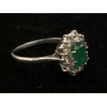 A diamond and emerald dress ring