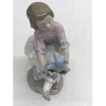 A Lladro figure of a girl holding a teddy bear,