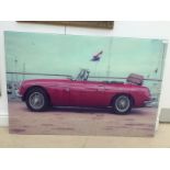 A large colour print on glass panel of an MGB GT motor car,