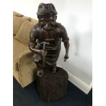 A large 19th century carved figure of a blacksmith on a wooden base (H 34";