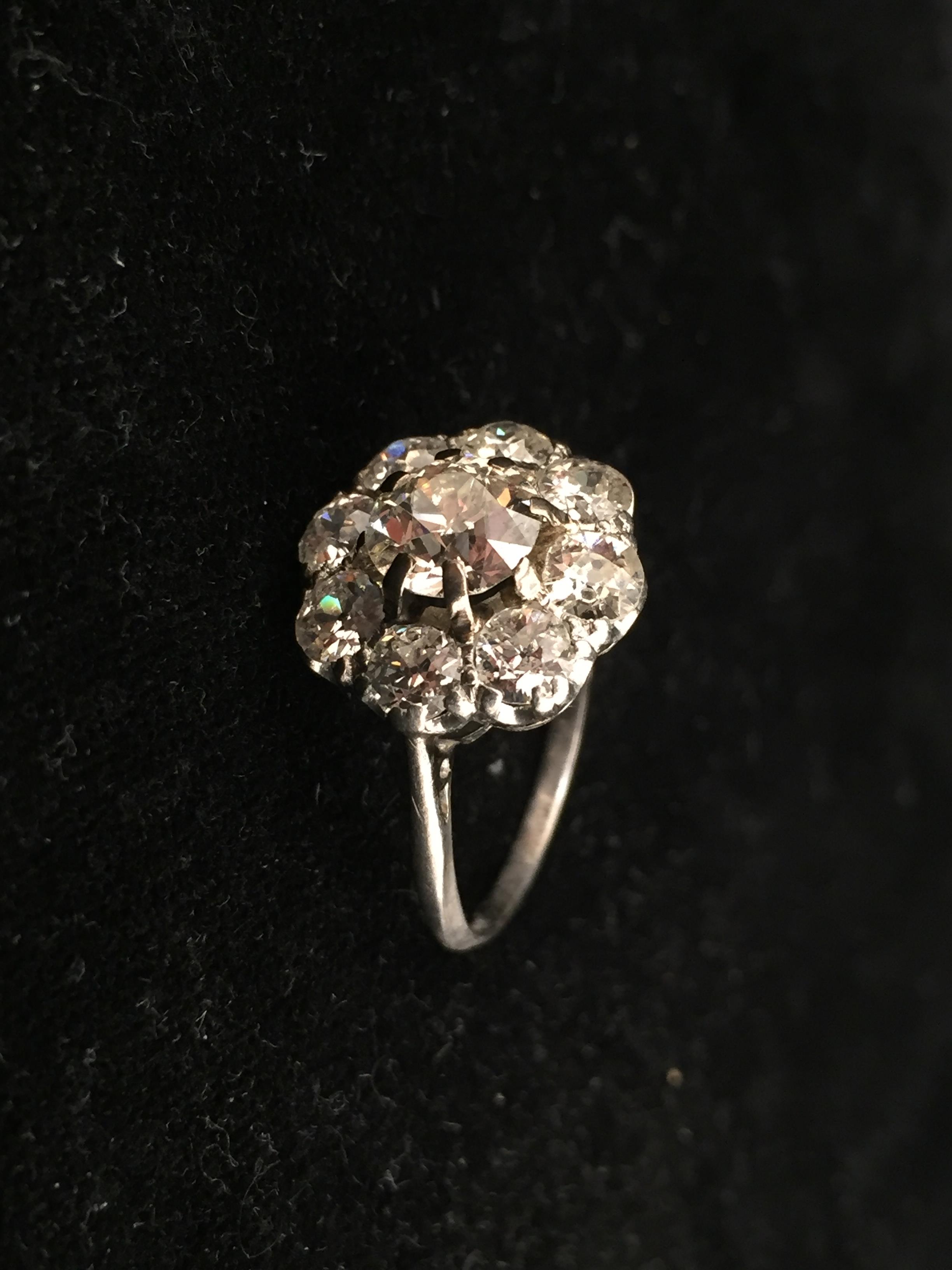 A platinum diamond daisy ring, central old brilliant cut stone: spreads 1.5ct; Moes measure 1.