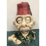 A cast-iron money box in the form of a man in a fez