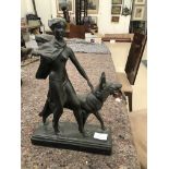 An art deco plaster figure of a lady walking a german shepherd