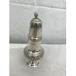 An HM silver sugar shaker with foliate designs and finial