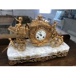 A 19th/20th century gilt clock set in a carriage ridden by putti on a marble base with applied