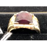 A gentleman's 10k gold ring set with harlequin faceted red stone