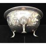 A HM silver three legged bowl, on pad feet embossed with Indian farm scene,