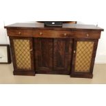 A Regency mahogany side cabinet with three frieze drawers above two panel wireworked doors and two