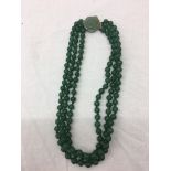 A jade three-strand bead necklace with carved floral jade clasp