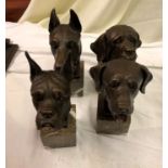 A set of four cast bronze dog heads on marble bases