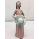 A Lladro figure of a girl holding a hat