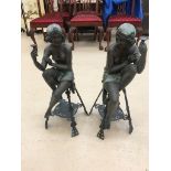 A pair of Art Deco-style bronze figures depicting a half-nude couple of young women sitting on high