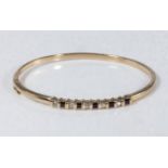 A 9ct gold bangle set with sapphires and diamonds