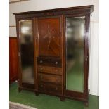 An Edwardian mahogany double mirrored door wardrobe with centre drawers and cupboard